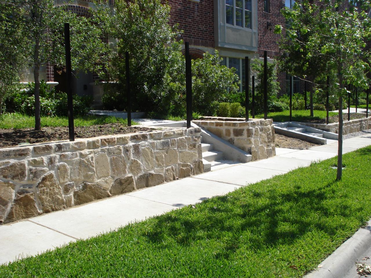Structural Austin stone retaining wall with integrated fence footings