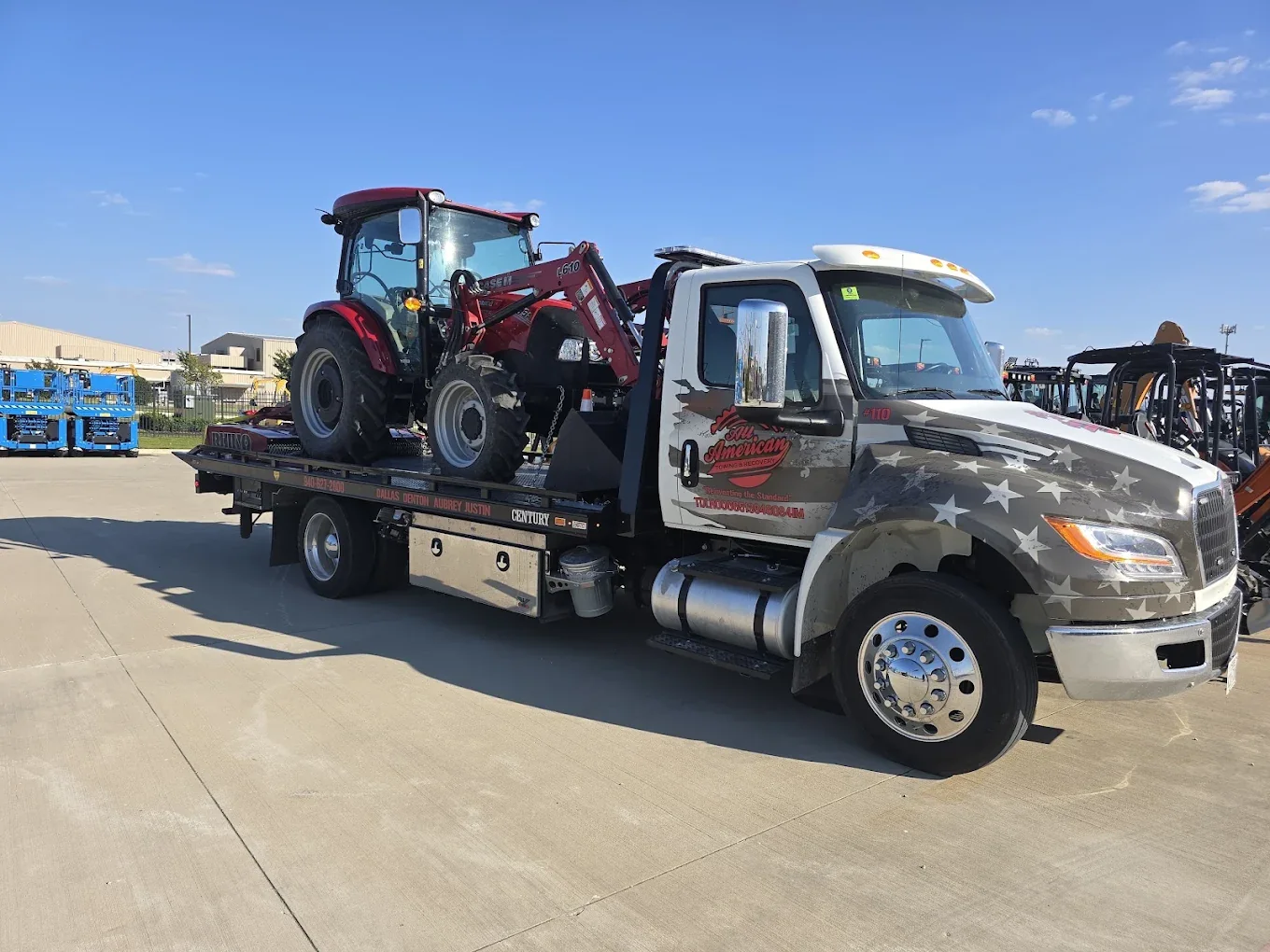 All American flatbed transporting heavy equipment