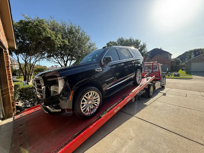 Black GMC Yukon secured on an All American red flatbed