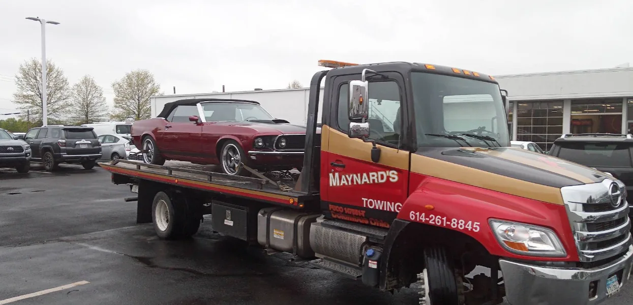 Maynard's flatbed towing a classic red Mustang